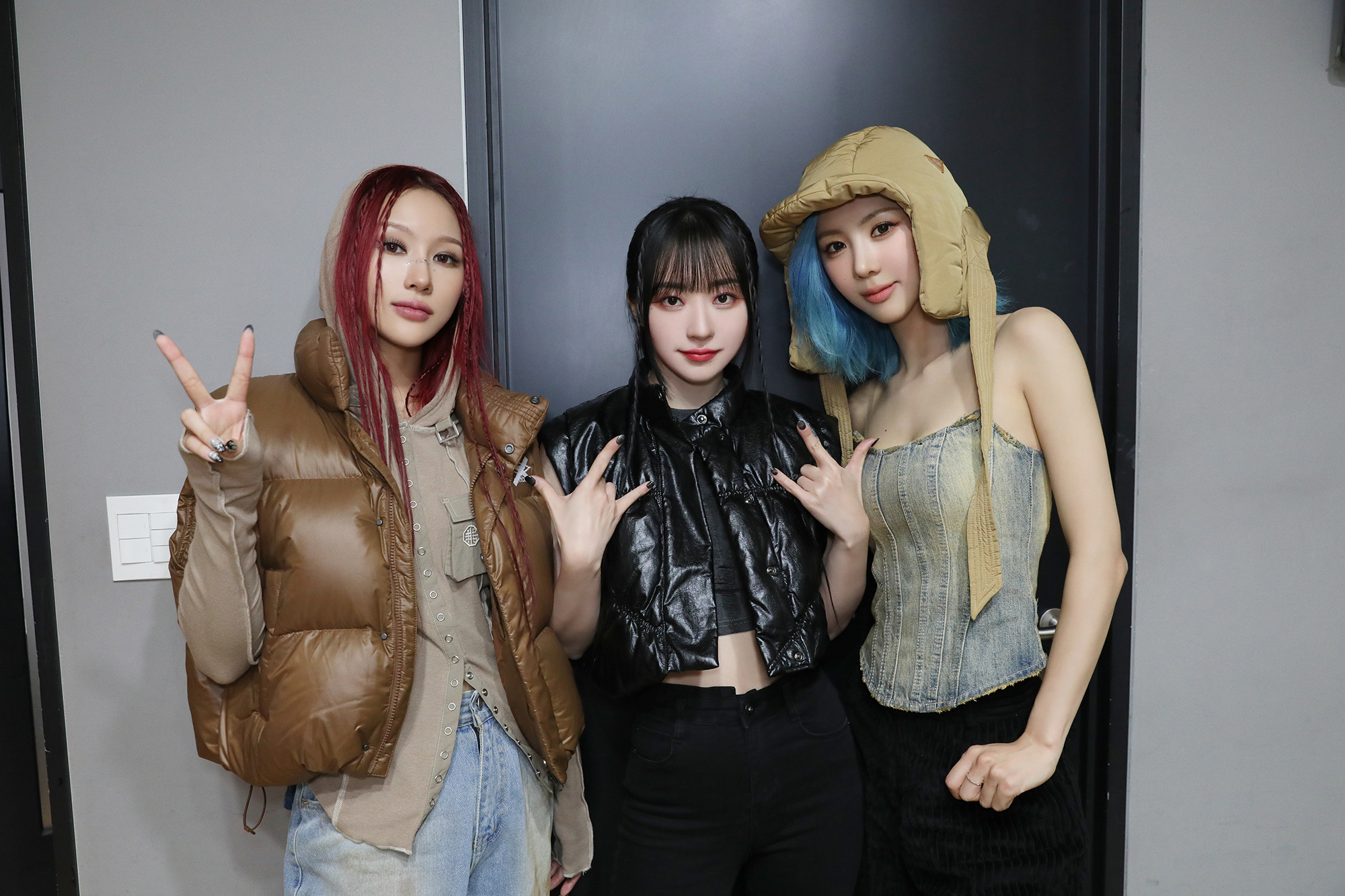 Siyeon, SuA and Yoohyeon dressed in casual and rock-style outfits for a music show.